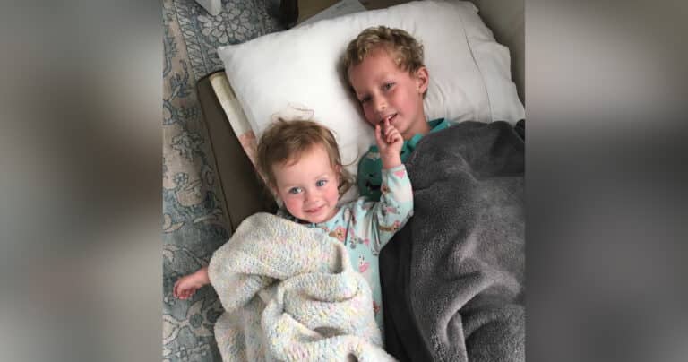 Toddler girl lying with big brother, color photo