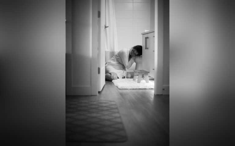 Pregnant women on floor next to toilet, black-and-white photo