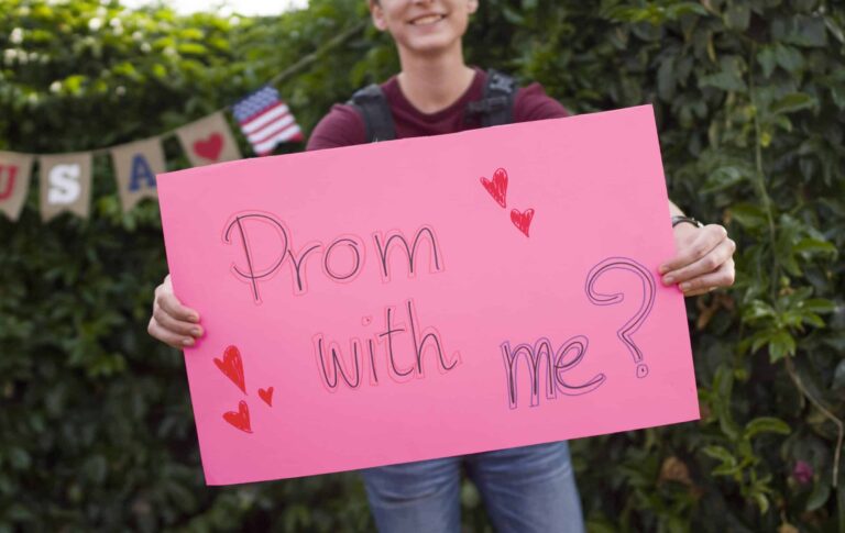 Boy holding pink sign saying "Prom with me?"