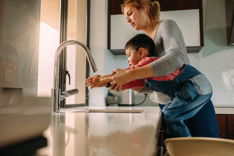 Mother helping son wash hands