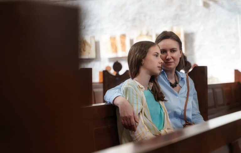 Woman and teen daughter in church pew