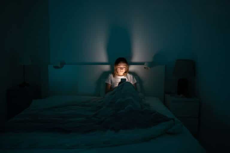 Woman alone in bed with phone