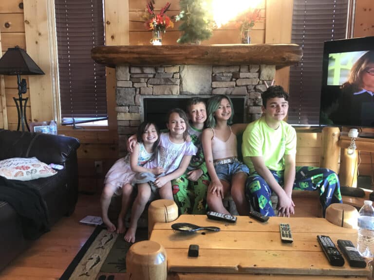 Five kids sitting next to fire place, color photo