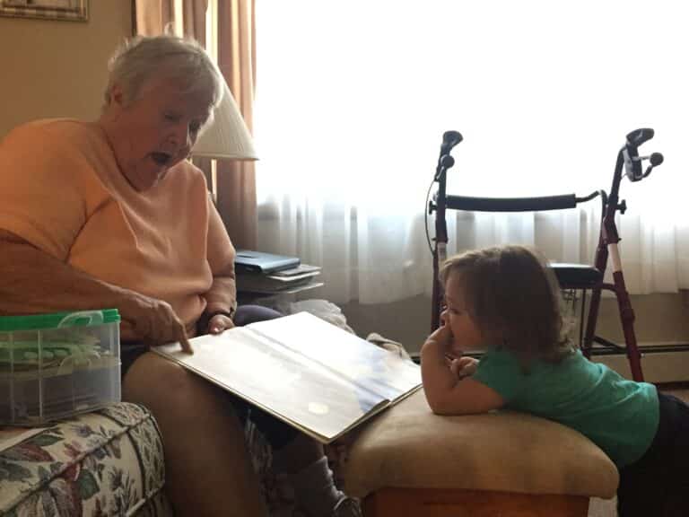 Grandmother reading book to granddaughter, color photo