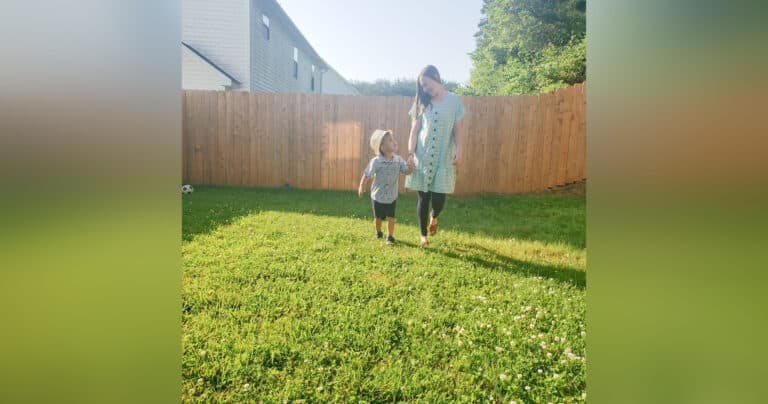 Mother and child walking in backyard, color photo