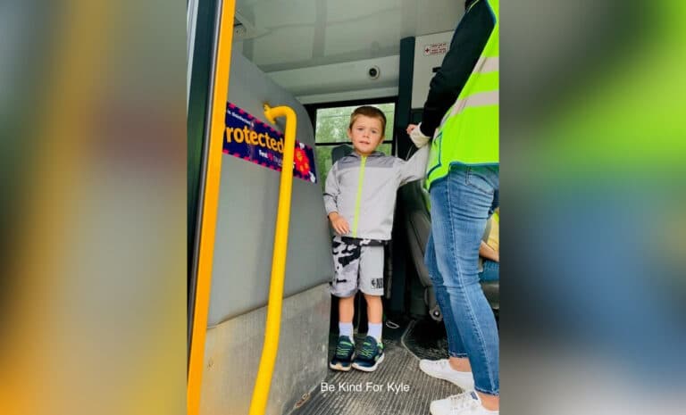 Little boy standing on school bus stairs, color photo