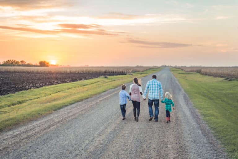 Family walking on farm road at sunset