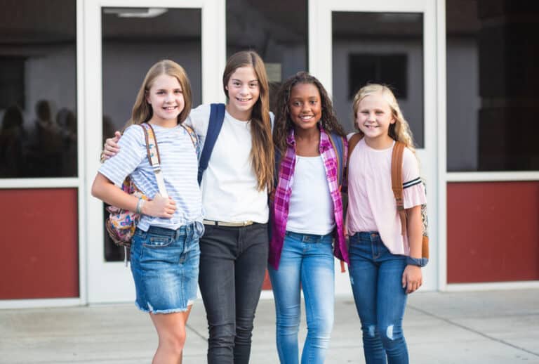 Group of tween girls in front of school smiling
