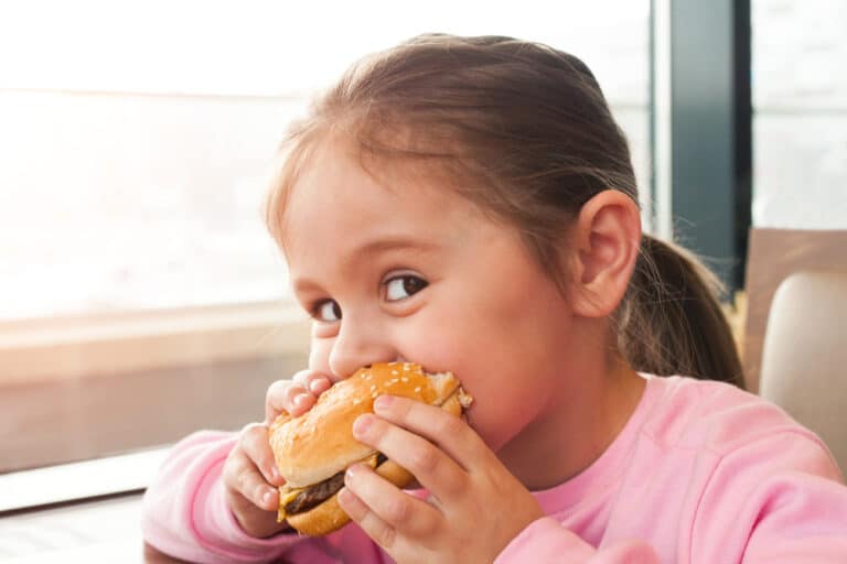 Little girl eating fast food cheeseburger