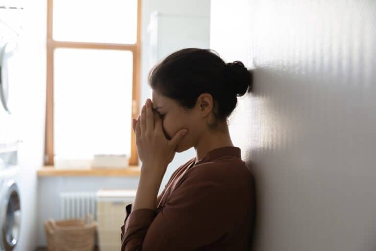 Overwhelmed woman leaning against wall