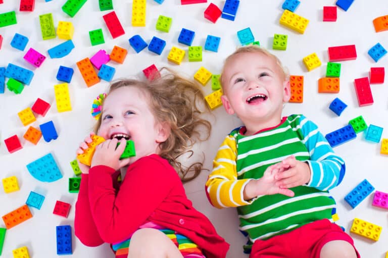 Toddlers laughing with building block toys around them