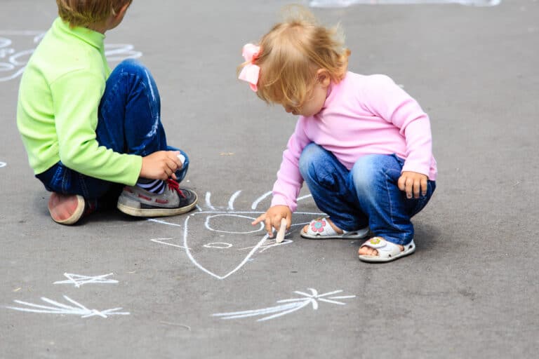 toddler boy and girl draw with sidewalk chalk