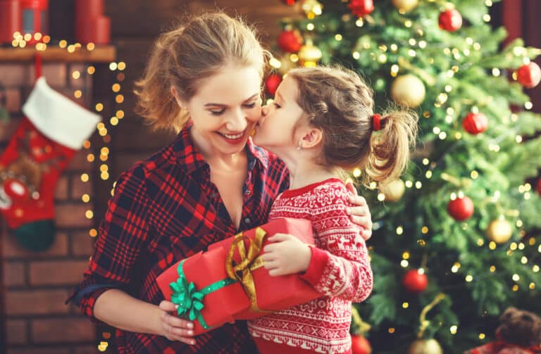 Daughter kissing mother and giving her Christmas gift