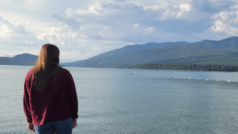 Woman staring out at lake, color photo