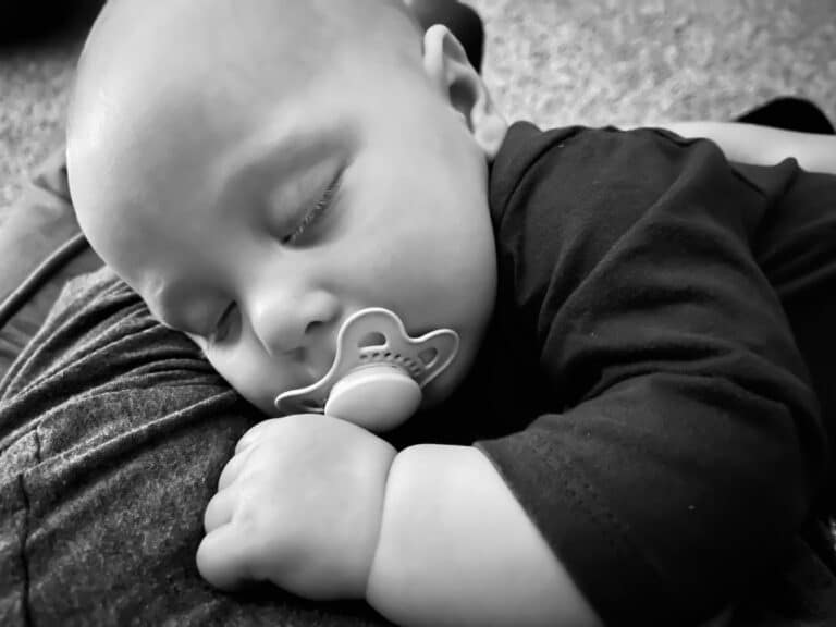 Black and white photo of baby sleeping with pacifier in his mouth