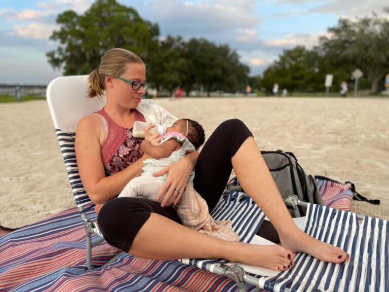 Woman holding baby on beach, color photo