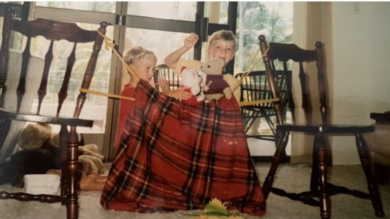 Two children behind blanket with puppets, color photo