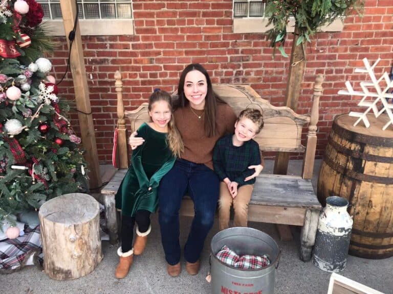 Mom and two kids smiling by Christmas tree