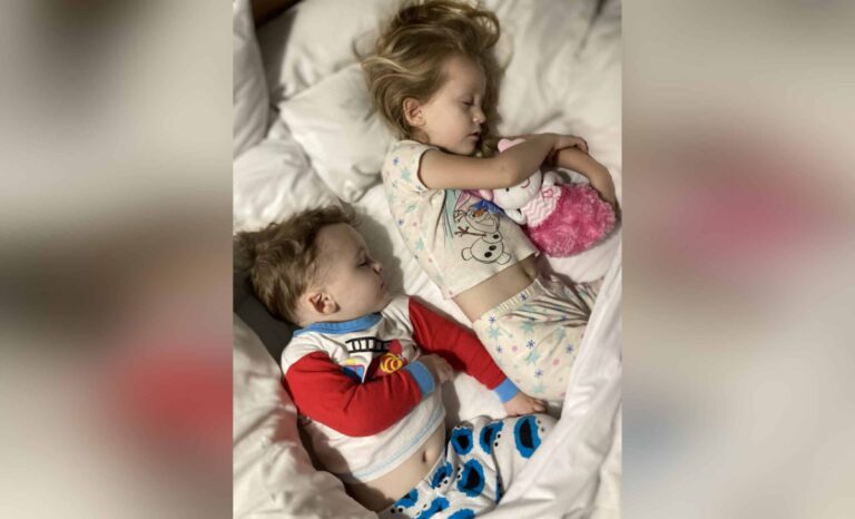 Two children lying in bed, color photo