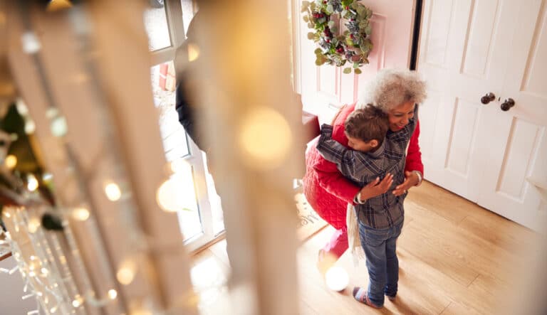 Grandchild hugs grandma in entryway at Christmas