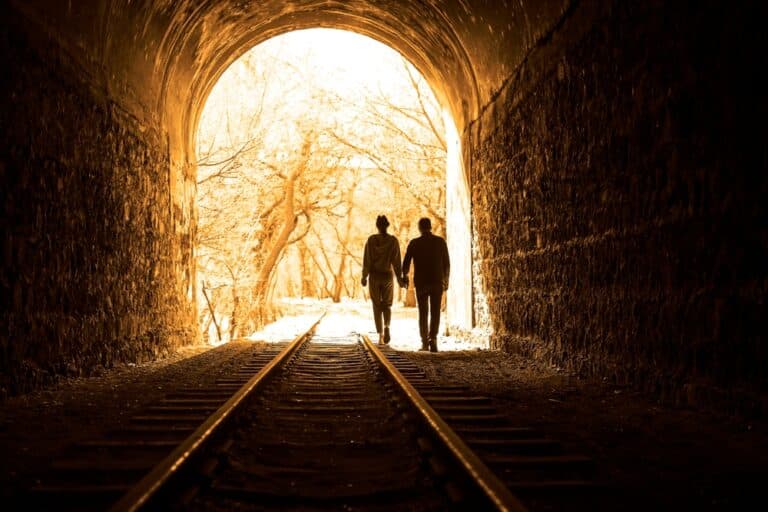 Couple walking down tracks in a tunnel