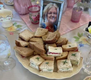 tea sandwiches on a fancy plate with photo of woman in frame