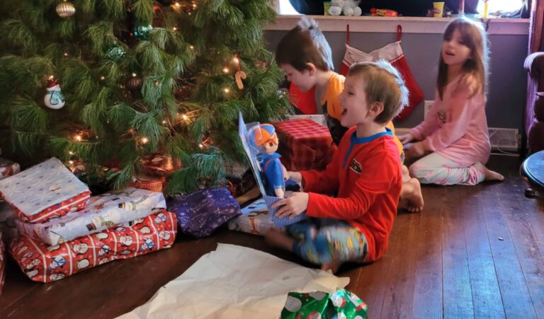 Kids under the Christmas tree opening gifts, color photo