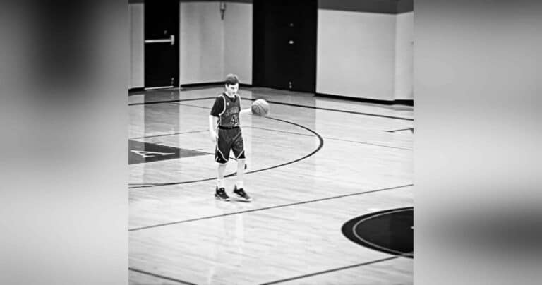 Boy dribbling down basketball court, black-and-white photo