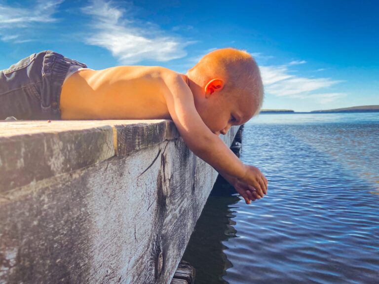 Little boy hanging over dock, color photo