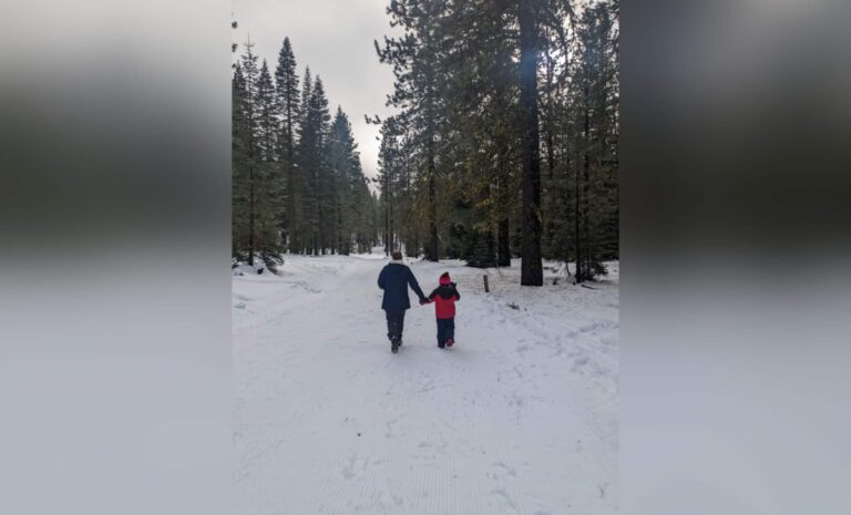 Mother and daughter walking down snowy path, color photo