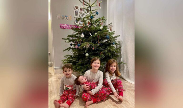 Four children in front of Christmas tree, color photo