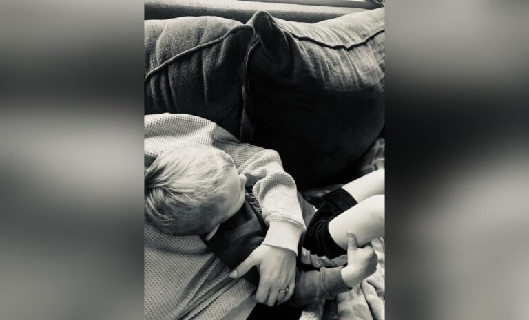 Woman holding boy on couch, black-and-white photo