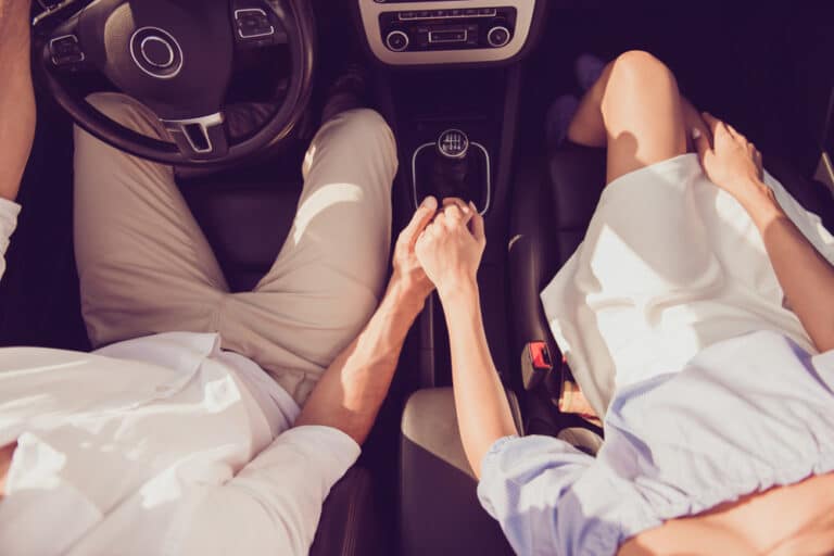 Couple holding hands in car, above view