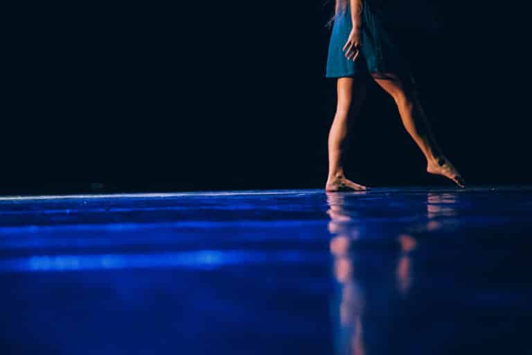 Feet of a young dancer on darkened stage