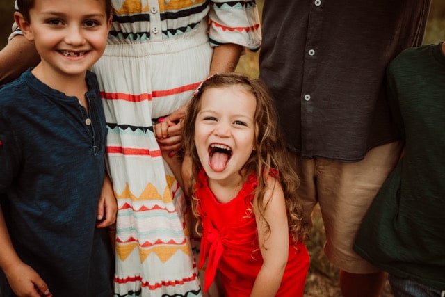 Little girl sticking her tongue out with her brother and parents, color photo