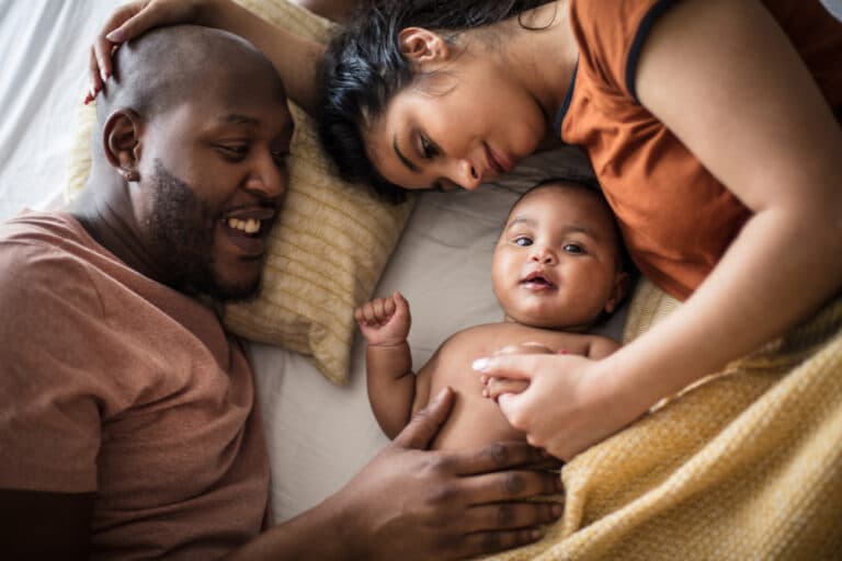 Family of 3 with baby on bed