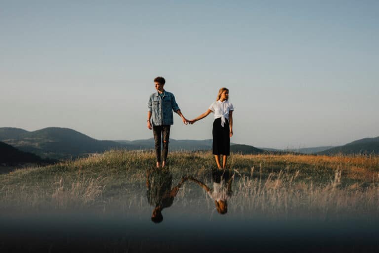 Couple standing holding hands by water