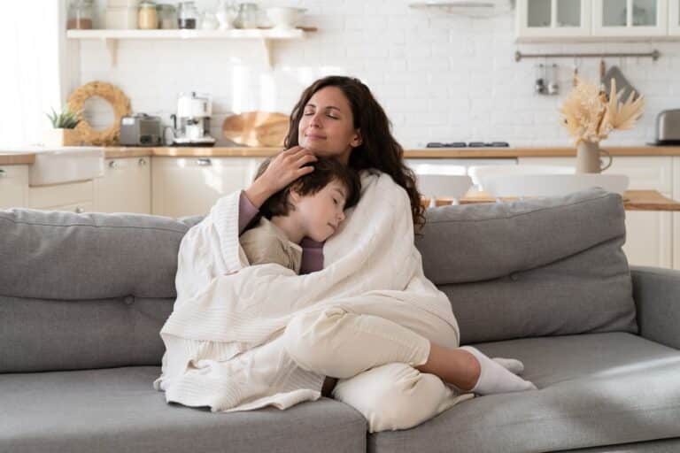 Mom and child sitting in a blanket on the couch