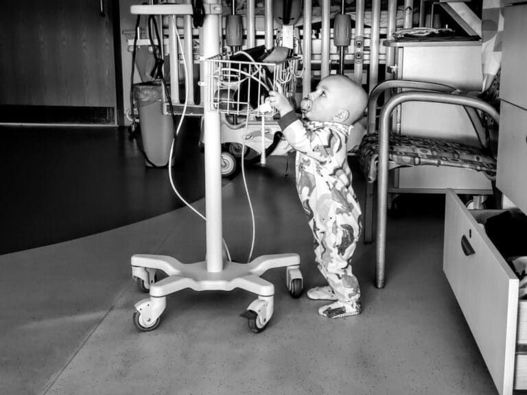 Toddler standing with IV pole, black-and-white photo
