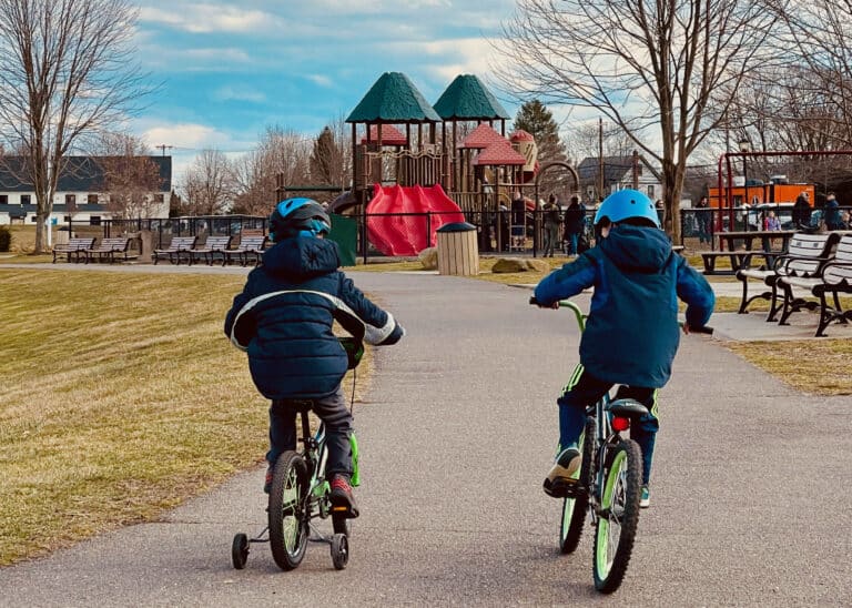 Two boys on bicycles riding to park, shown from behind