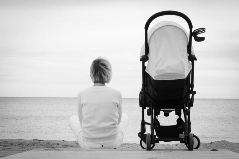 Mom sitting beside stroller, black and white image