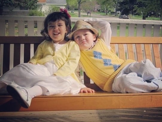 Brother and sister in yellow outfits smiling on park bench