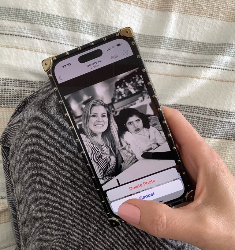 Woman holding phone with picture of her and daughter, color photo