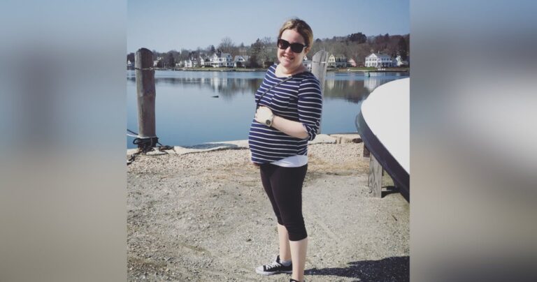 Pregnant woman standing lakeside, color photo