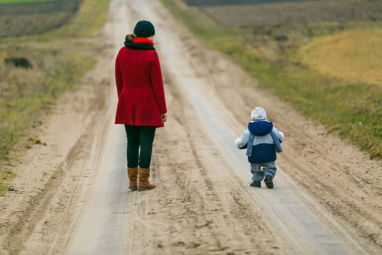 Mom standing with child on dirt road