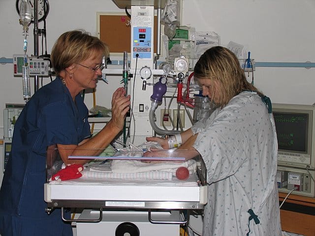 Mom and nurse with baby in NICU, color photo