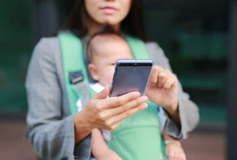 Businesswoman holding baby and phone