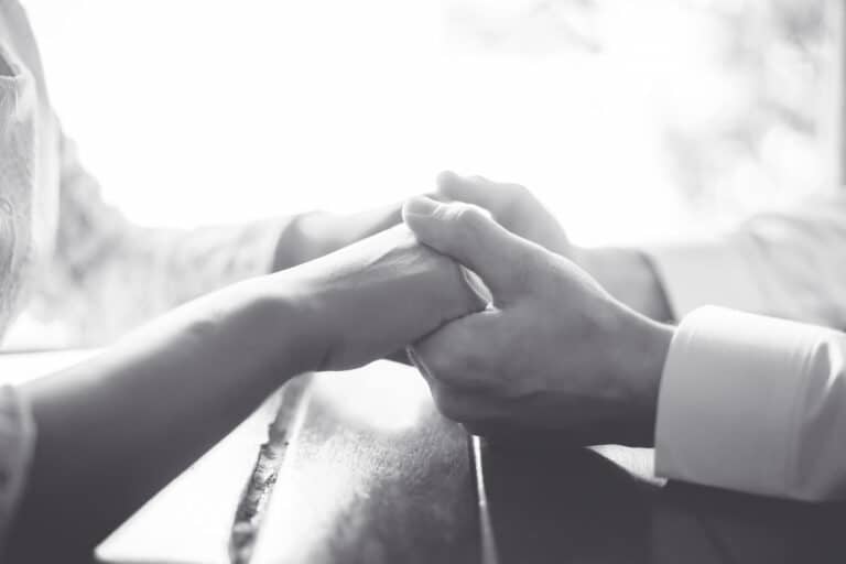 Coupe holding hands at wedding, close up black and white image