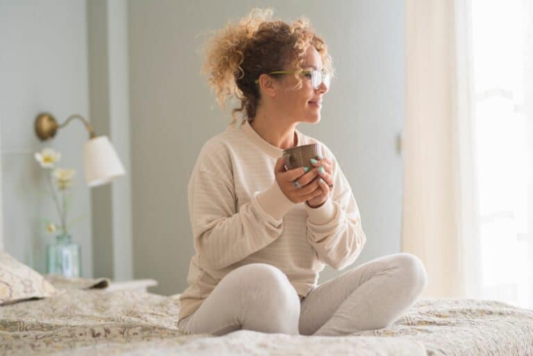 Woman sitting on bed with coffee mug