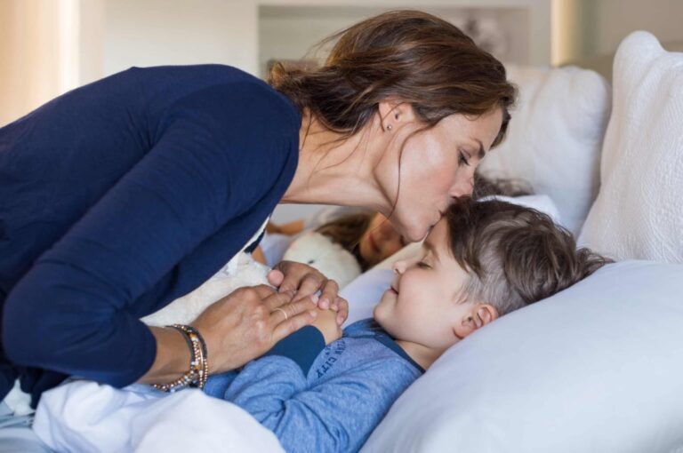 Mother kissing son goodnight, color photo
